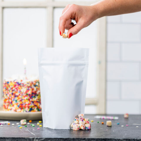 hand dropping birthday cake pieces into a white pouch