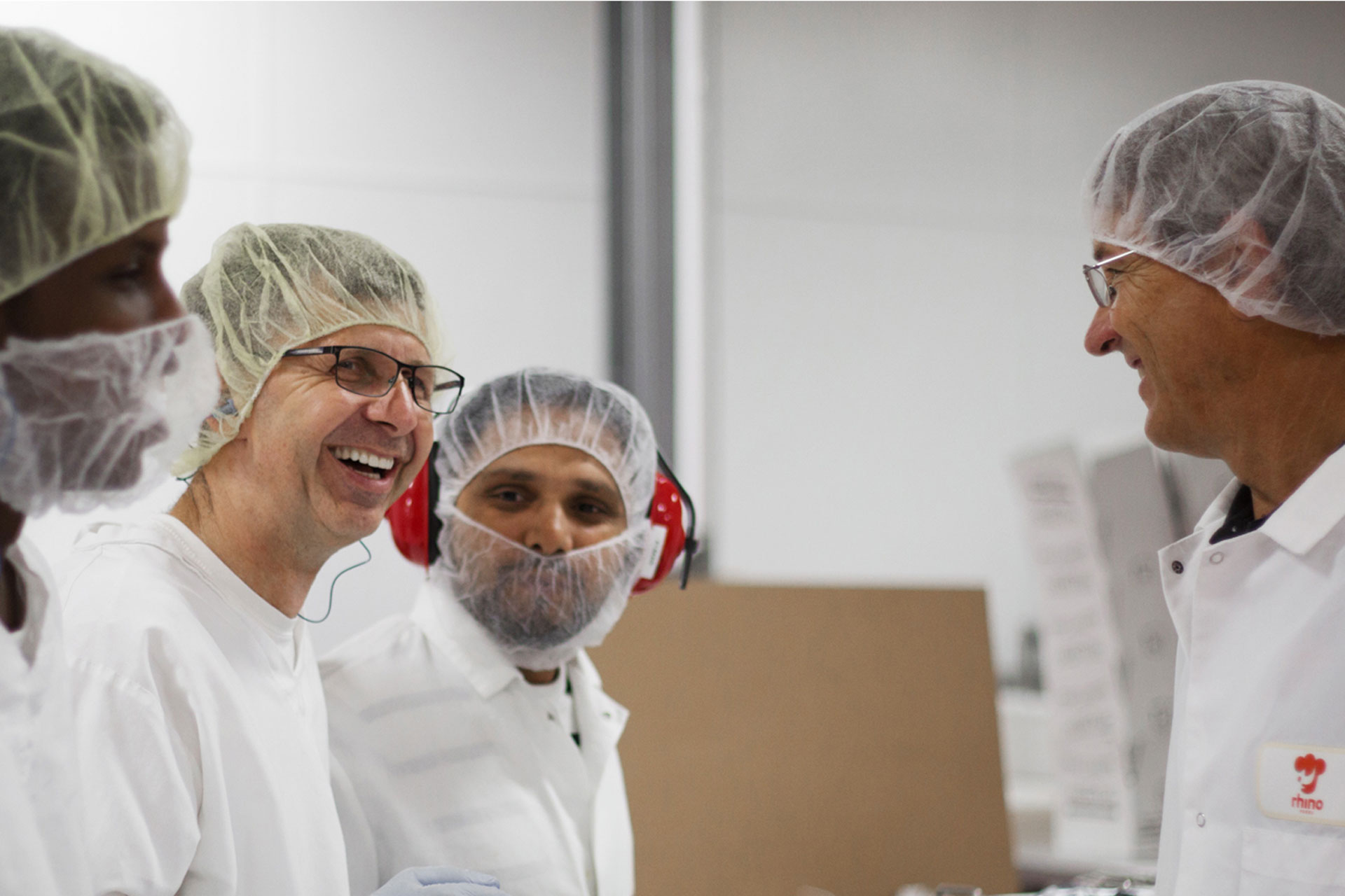 Five Rhino workers smiling while talking to Ted Castle, Owner