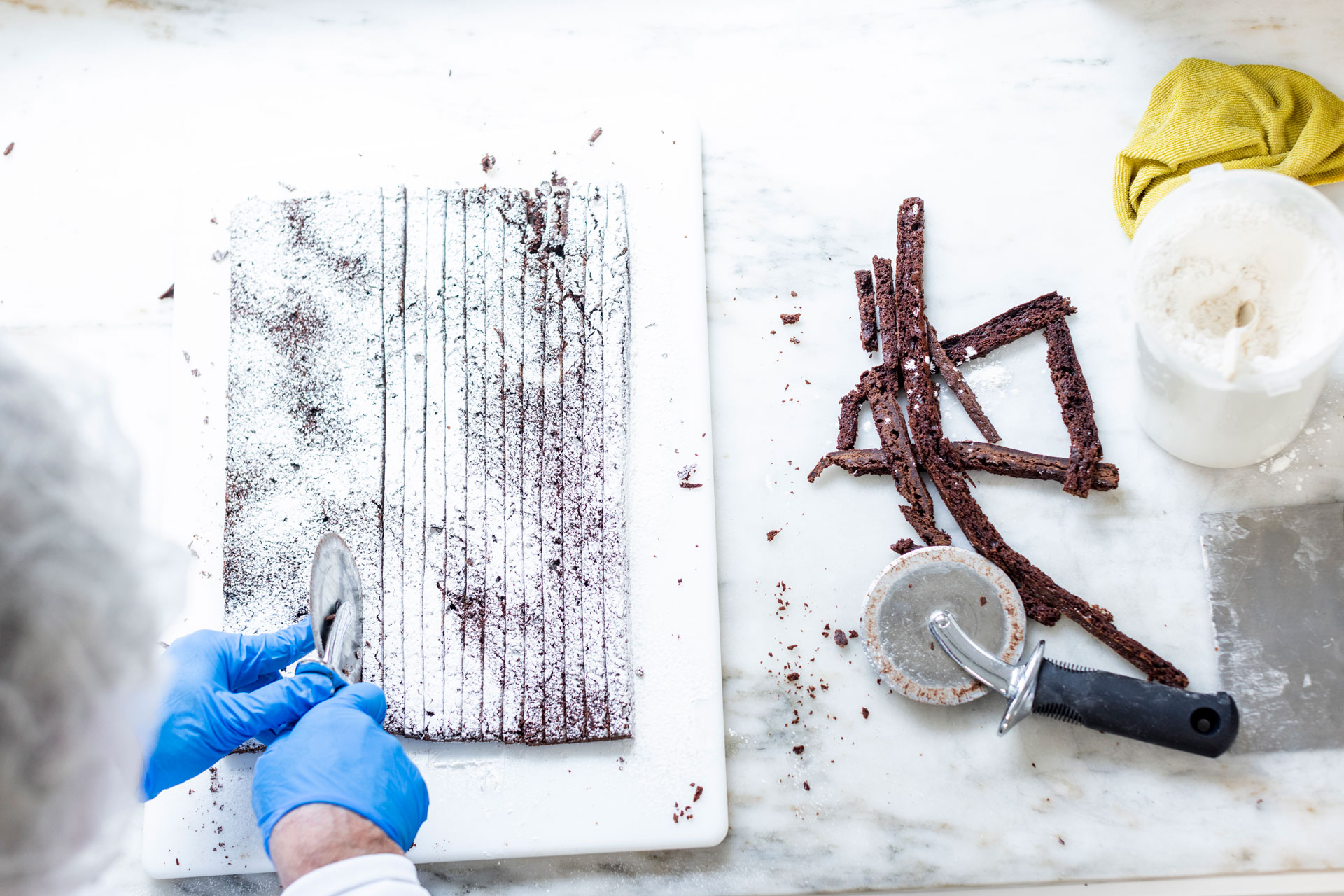 Gloved hands cutting brownies